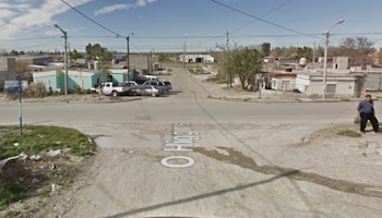 Vista de la intersección de una calle con el texto O'Higgins en el suelo, casas bajas, postes con cables aéreos y un hombre caminando