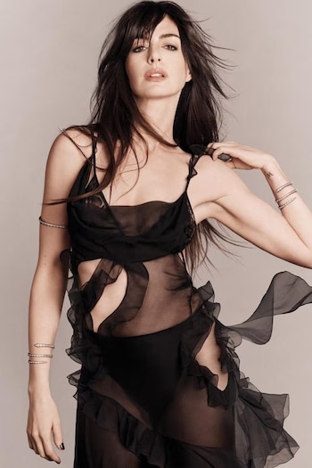 Hathaway explora la dualidad entre fragilidad y fuerza con un vestido negro de gasa y brazaletes de serpiente, evocando una fantasía nocturna de inspiración noventera (Vogue)