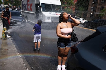 Personas aprovechan el agua de un hidrante abierto en Manhattan para refrescarse durante uno de los días más calurosos registrados en abril y mayo de 2026.