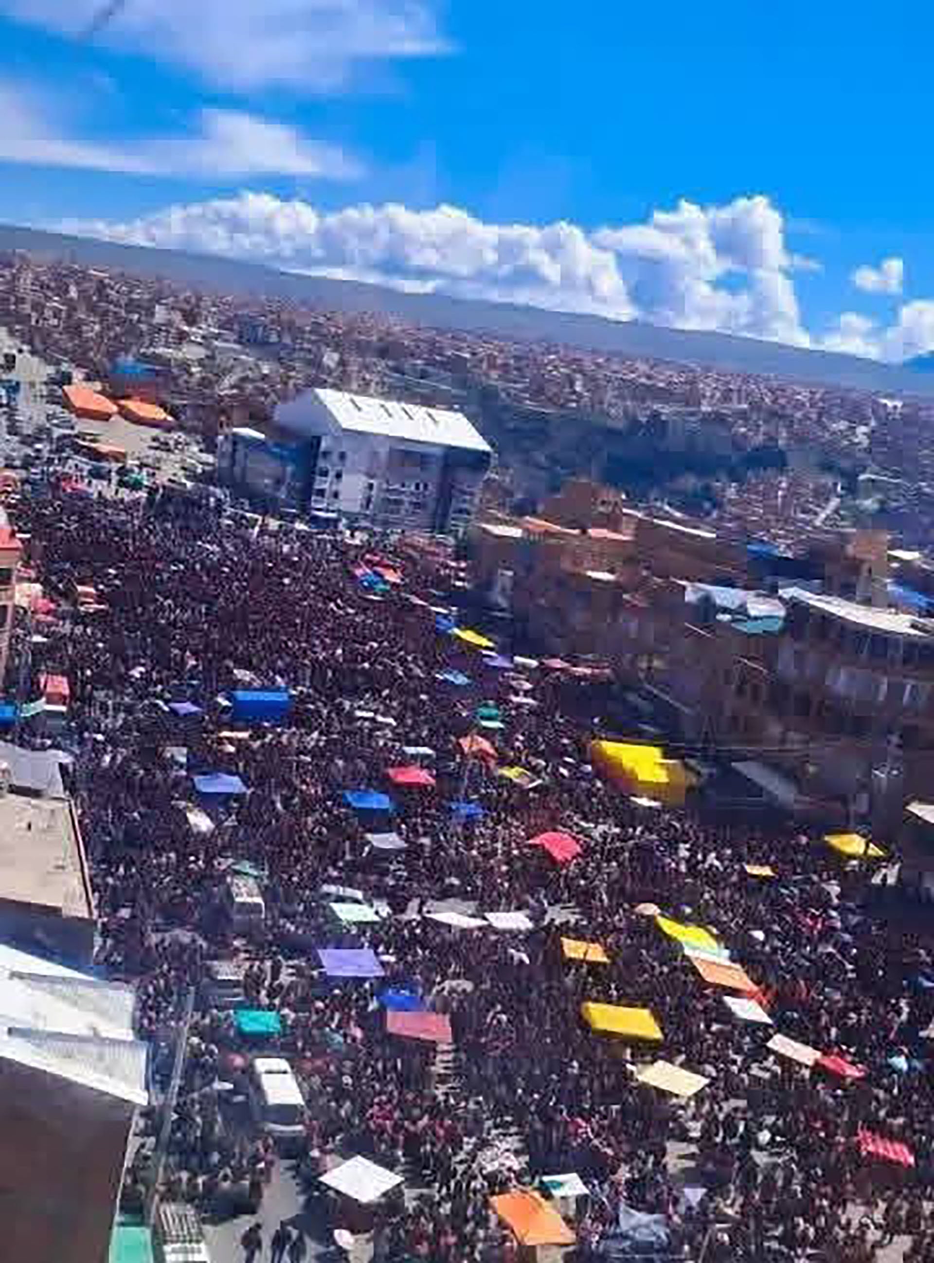Una vasta multitud se congrega en un cabildo abierto en la ciudad de El Alto, Bolivia, con toldos coloridos y edificios, reflejando una masiva participación ciudadana.
