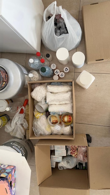 Cajas con miles de píldoras de varios colores en bolsas, botellas llenas de pastillas y un saco de frascos vacíos sobre un suelo de baldosas