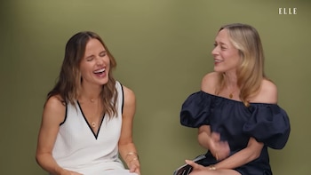 Jennifer Garner a la izquierda, riendo con los ojos cerrados, y Chloë Sevigny a la derecha, sonriendo. Ambas sentadas frente a un fondo verde liso. Logotipo ELLE