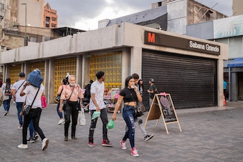 Personas pasan frente a una estación del sistema metro de Caracas cerrada por la réplica de magnitud 4,6 registrada este lunes (EFE/ Rayner Peña R)