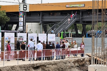 Un grupo de personas observa paneles informativos en una obra de construcción junto al paradero de autobuses del CETRAM Universidad