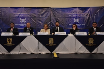 Seis autoridades sentadas ante una mesa con rótulos de sus nombres y cargos, con un fondo azul del Tribunal Supremo Electoral