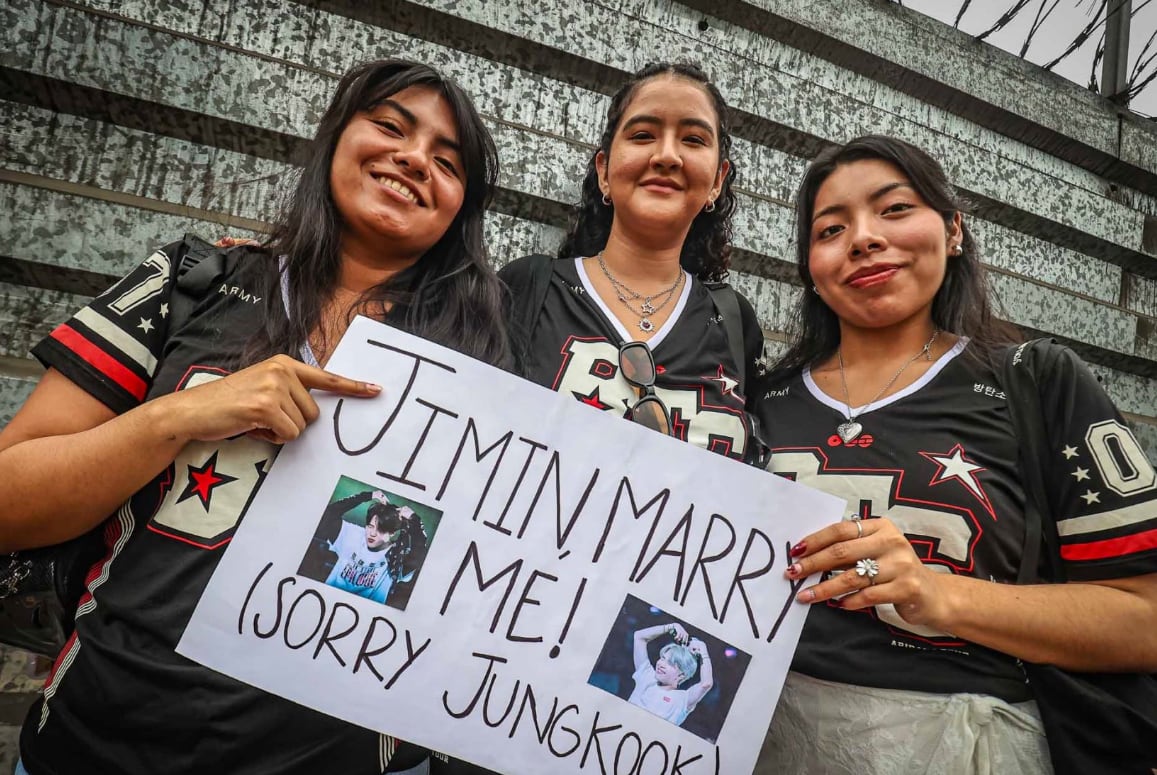 Tres seguidoras del grupo surcoreano BTS sostienen un cartel manuscrito en las inmediaciones del Estadio San Marcos. (Agencia Andina)