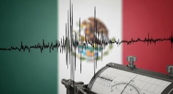 Primer plano de un sismógrafo real con líneas sísmicas negras sobre un fondo desenfocado de la bandera de México en verde, blanco y rojo.