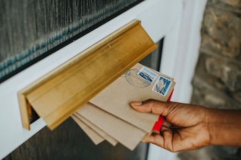 Una mujer cogiendo las cartas del buzón (Freepik)