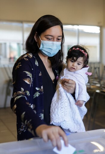 Una mujer vota sosteniendo a