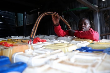 Un vendedor de agua, llena garrafas con una manguera desde un tanque, en el vecindario humilde de Kibera, en Nairobi, Kenia, el 21 de marzo de 2023. (AP Foto/Brian Inganga)
