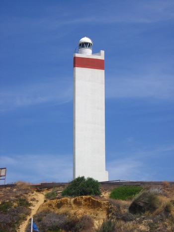 faro blanco de base triangular con una línea roja