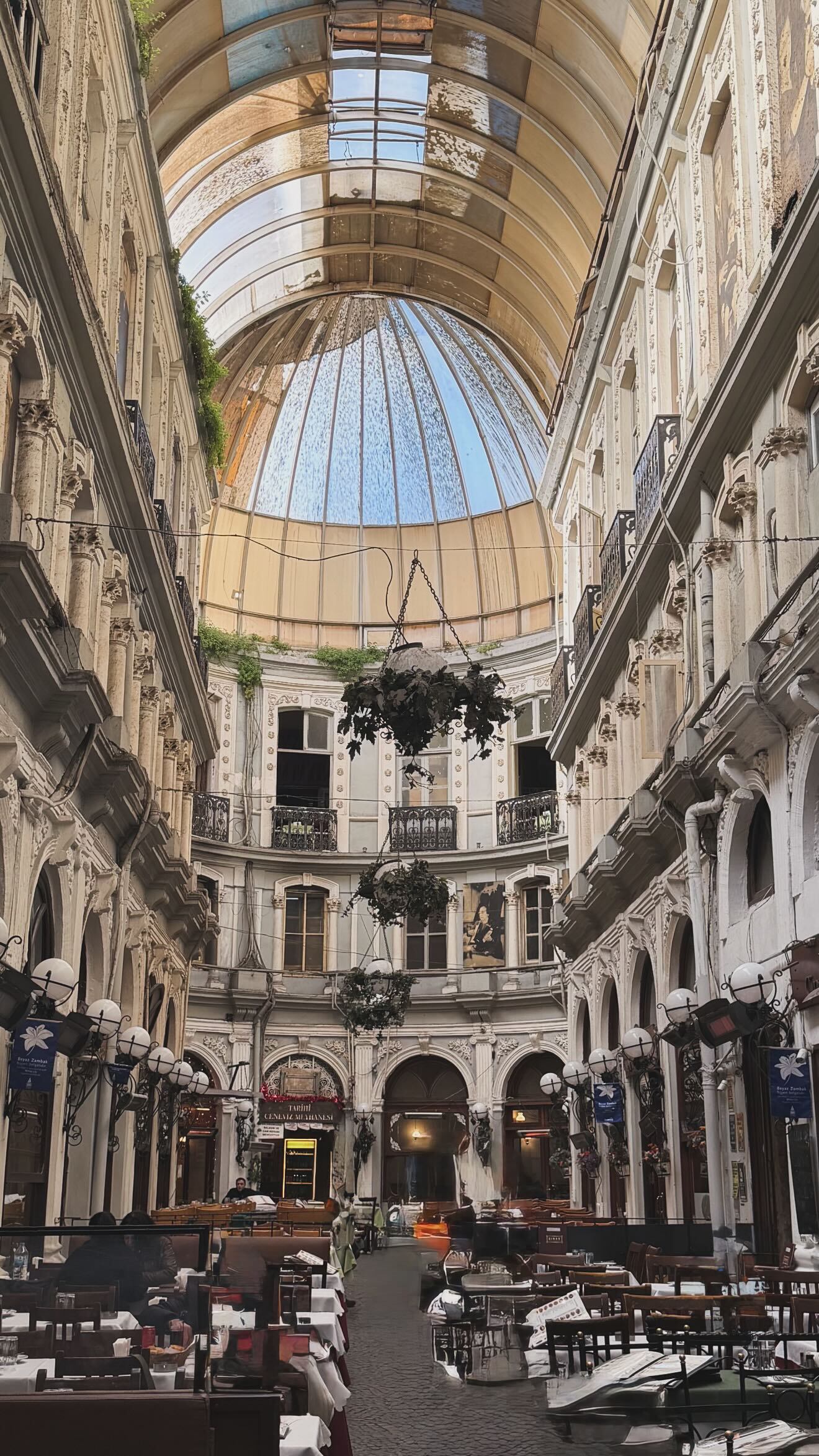 Una impresionante galería histórica en Estambul, adornada con una cúpula de cristal y detalles ornamentados, ofrece un espacio vibrante para el turismo y el ocio