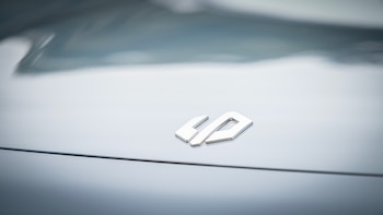 Logo metálico plateado de Leapmotor sobre una superficie brillante gris de vehículo con una línea horizontal