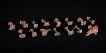 Una docena de clavos metálicos oxidados y algunos pequeños fragmentos de madera antigua, presumiblemente de un barco, sobre un fondo negro