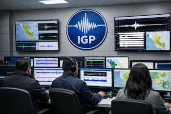 Sala de monitoreo sísmico con tres operadores frente a múltiples pantallas que muestran mapas sísmicos de Perú y gráficos de ondas, y el logo del IGP.