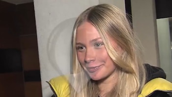Primer plano de una mujer joven rubia con pelo largo y una chaqueta amarilla. La mujer sonríe mirando ligeramente a la derecha
