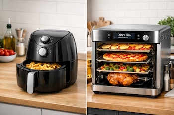 Una freidora de aire negra con papas fritas al lado de un horno inteligente plateado que cocina pollo, pizza, vegetales y fruta deshidratada en una cocina.