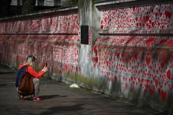 Una mujer toma una foto del mural que recuerda a las víctimas de COVID-19 en Londres, Reino Unido (Foto: REUTERS/Hannah McKay)