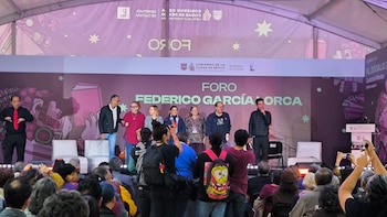 Un escenario con la inscripción Foro Federico García Lorca, varias personas de pie ante el público y un intérprete de lengua de señas