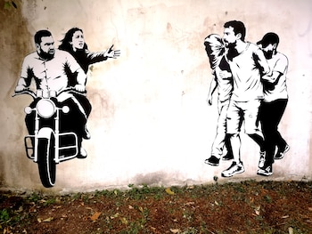 Pared exterior con un mural en blanco y negro que representa una motocicleta a la izquierda y tres personas caminando a la derecha