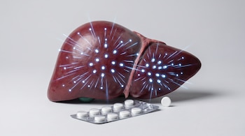 Modelo anatómico de hígado humano con esferas brillantes y líneas de energía azules. Junto a él, un blíster de pastillas blancas y una píldora suelta.