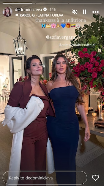 Sofía Vergara, con un vestido azul marino sin tirantes, y Eva De Dominici, con un traje granate y abrigo claro, posan sonriendo en un interior elegante con flores