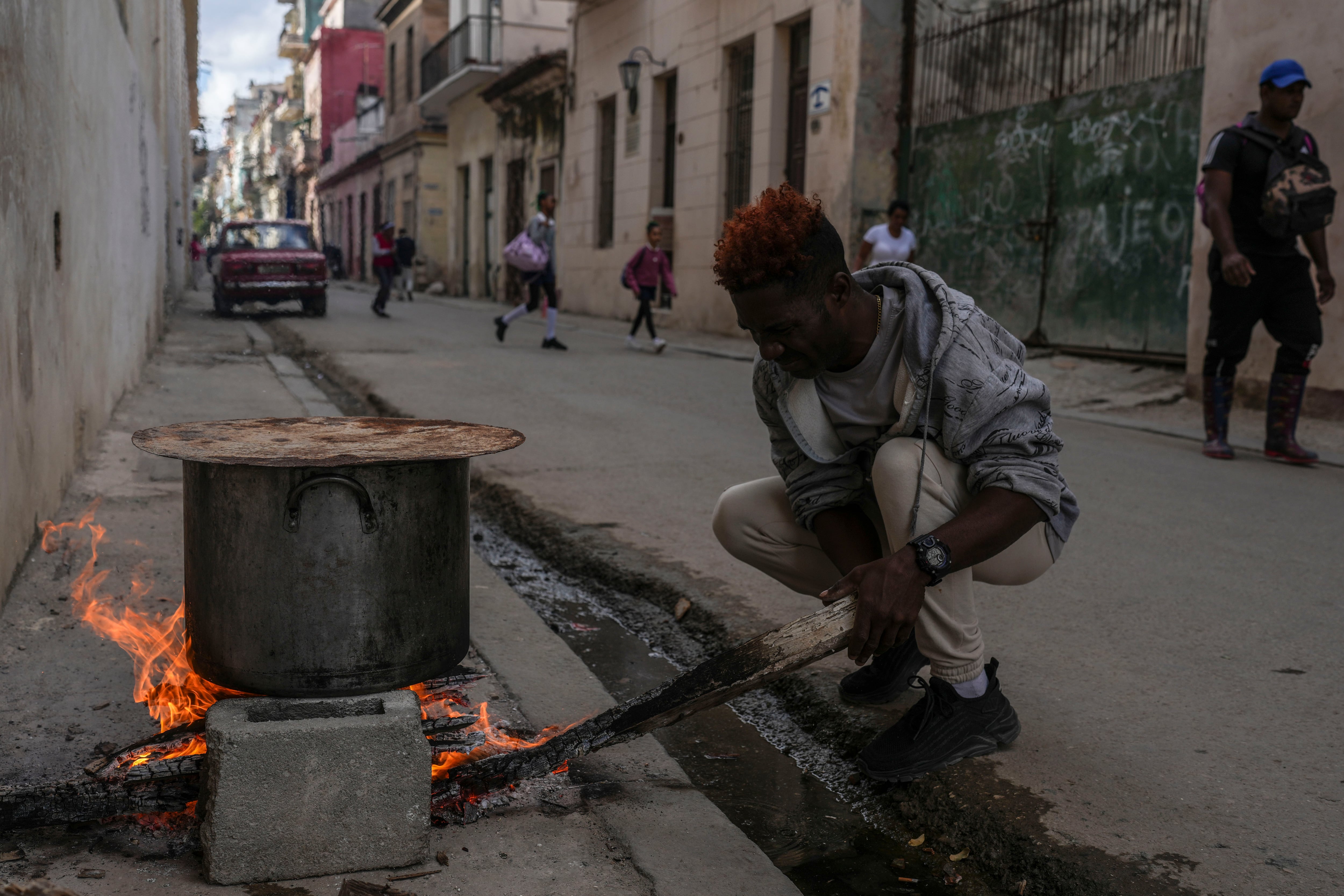 Un hombre cocina sopa sobre una fogata en una acera durante un apagón en La Habana, Cuba (AP Foto/Ramón Espinosa)