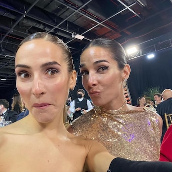 Juana Viale con vestido dorado de lentejuelas y Ámbar de Benedictis en top strapless posan para una selfie con muecas divertidas en un evento