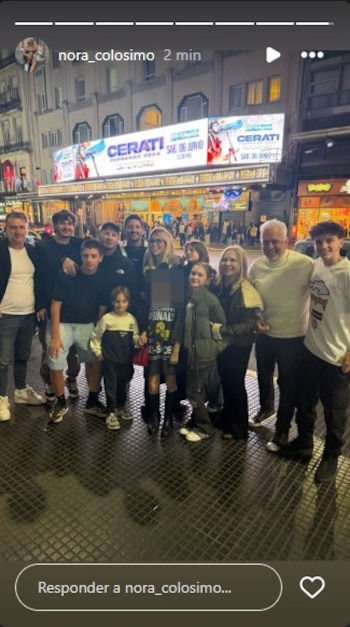 Grupo de doce personas, incluyendo a Wanda Nara y sus hijos, posando sonrientes de noche frente a la marquesina iluminada de un teatro con carteles