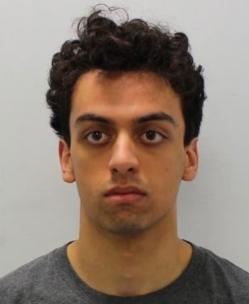 Retrato de frente de un hombre joven con cabello castaño rizado, ojos oscuros, boca cerrada y camiseta gris, sobre un fondo claro