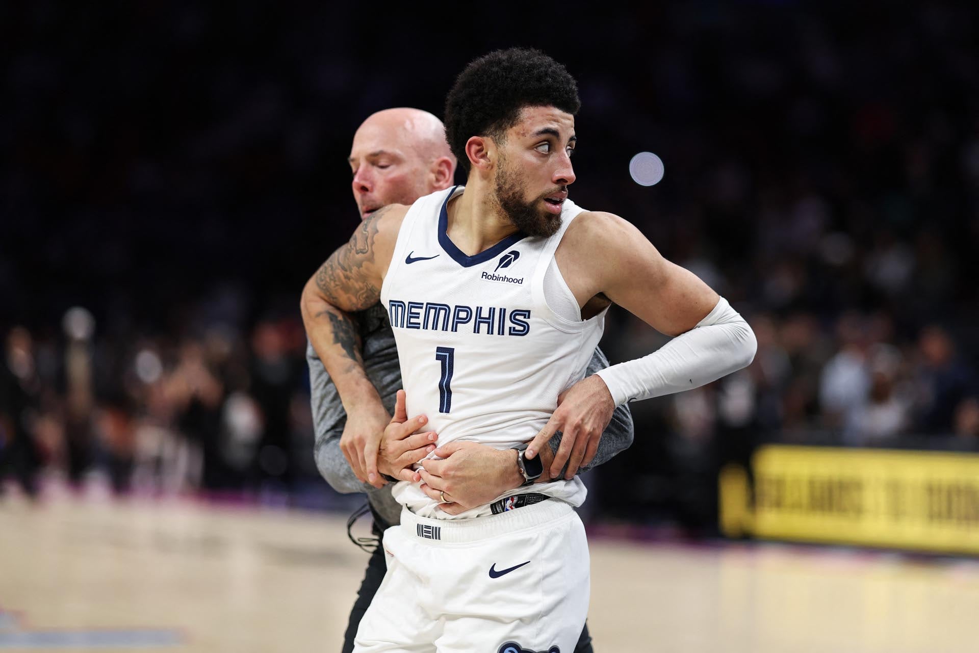 Scotty Pippen Jr., jugador de los Memphis Grizzlies, es asistido por un miembro del staff técnico en la cancha.