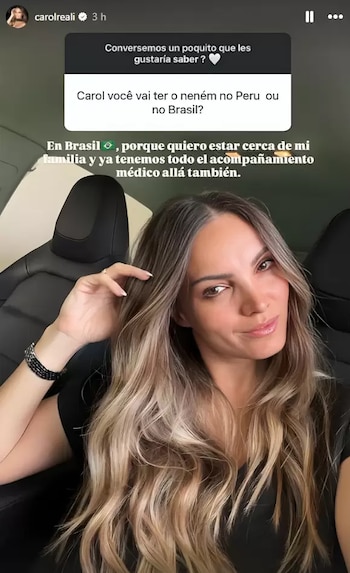 Mujer de cabello largo y ondulado con reflejos rubios, usa blusa negra y pulsera oscura, posa sonriendo dentro de un automóvil; hay un texto superpuesto