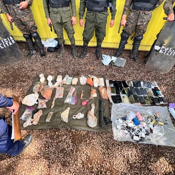 Cuatro agentes de Policía Militar y sus escudos, con numerosos teléfonos móviles, bolsas con contenido, cables y cargadores exhibidos en el suelo