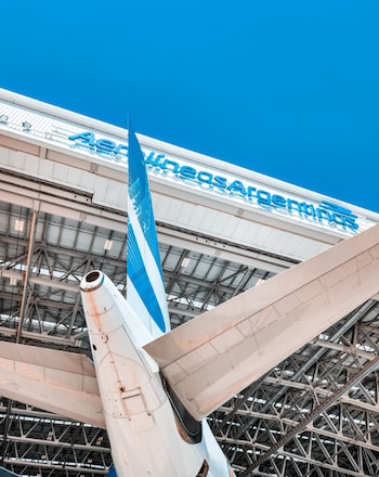 La parte posterior y la cola de un avión dentro de un hangar metálico con el cartel de Aerolíneas Argentinas