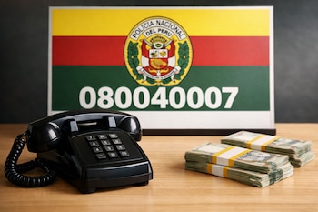 Un teléfono fijo negro sobre una mesa de madera clara, con pilas de billetes peruanos a su lado y un cartel de la PNP con el número 080040007 de fondo.
