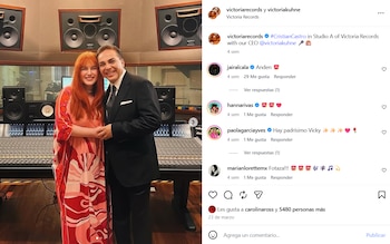 Victoria Kühne, con cabello rojo y vestido estampado, posa junto a Cristian Castro, vestido de traje, en un estudio de grabación con consola y monitores