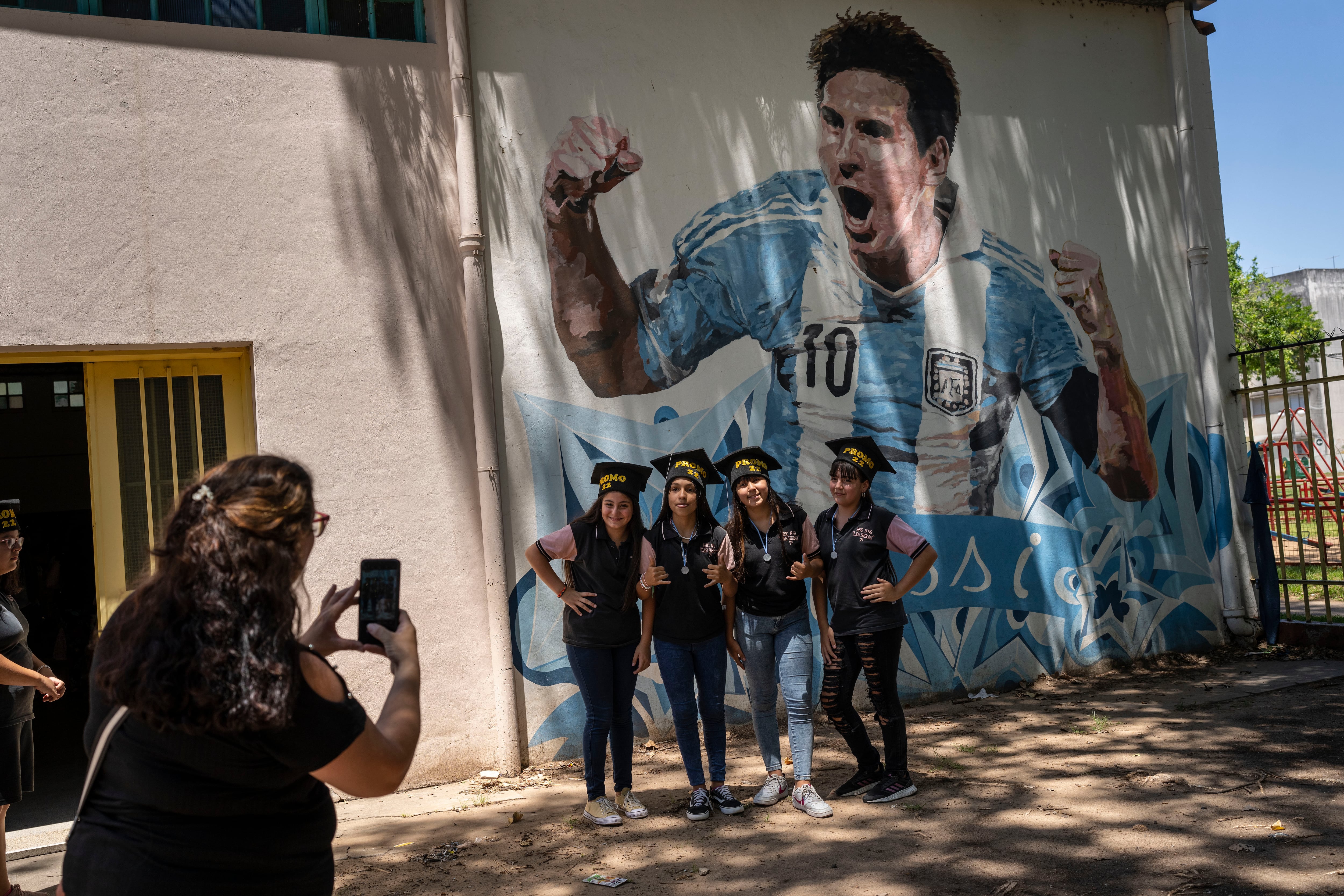 Estudiantes egresados de las escuela primaria General Las Heras posan frente a un mural de Messi, en el último día de clases. (AP Foto/Rodrigo Abd)