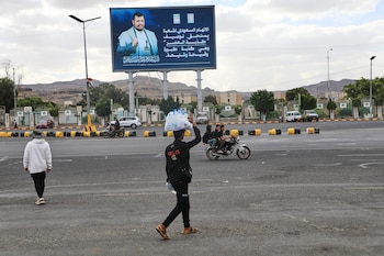 Un vendedor pasa bajo un cartel con la imagen del líder hutí Abdul Malik al-Houthi y la frase "la acusación saudí contra nuestra gente merece describirse como la mentira del siglo", en Saná, Yemen, el lunes 5 de octubre de 2026 (AP/Osamah Abdulrahman)