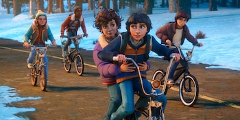 Cuatro personajes animados, dos de ellos compartiendo una bicicleta, pedalean por una carretera bordeada de nieve y árboles en un día invernal