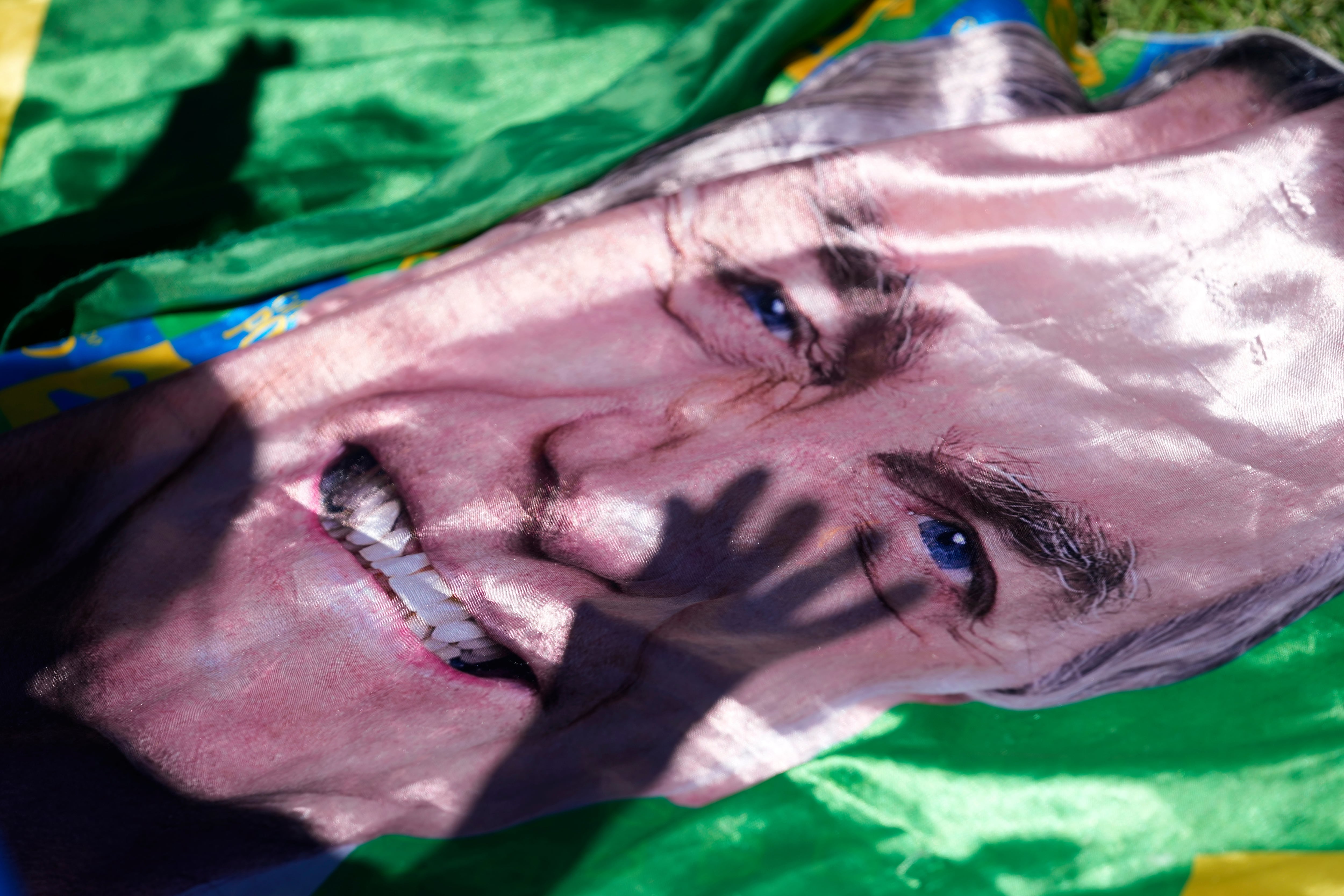 La sombra de un simpatizante del expresidente Jair Bolsonaro se proyecta sobre una imagen suya expuesta fuera del hospital donde fue trasladado de prisión para cirugía, en Brasilia, Brasil, el 24 de diciembre de 2025 (Foto AP/Eraldo Peres)