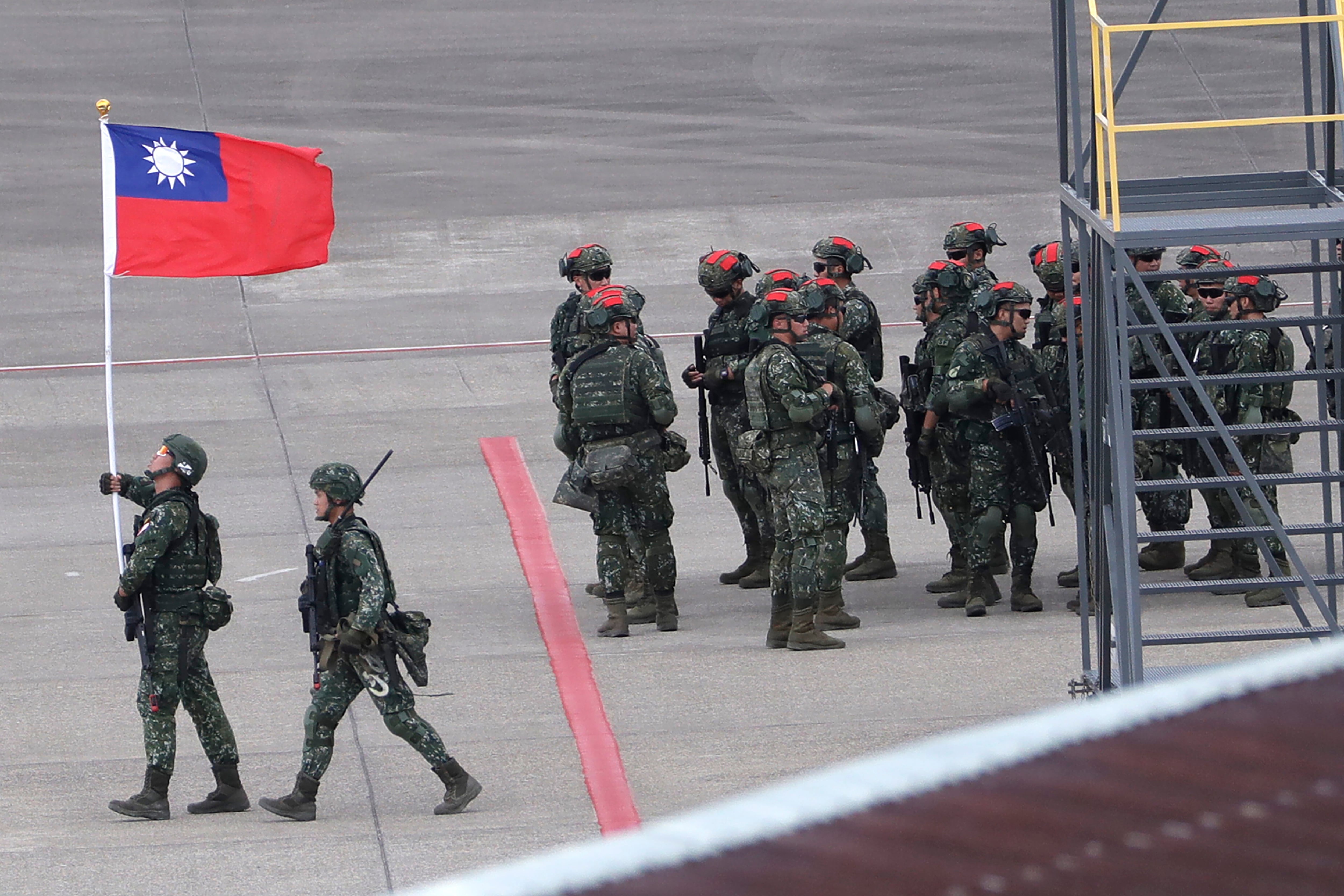 En esta imagen de archivo, un soldado taiwanés sostiene una bandera de Taiwán cerca de un grupo de soldados con marcas rojas en sus cascos porque se harán pasar por enemigos durante las maniobras anuales Han Kuang (AP Foto/Chiang Ying-ying, archivo)