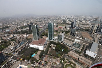 Vista aérea de un área urbana con rascacielos, edificios de oficinas, autopistas con vehículos, zonas residenciales y vegetación bajo un cielo brumoso