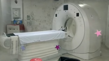 Un tomógrafo blanco con camilla cubierta por una sábana en una habitación médica sin personas