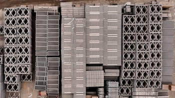 Vista aérea de estructuras metálicas y paneles modulares organizados y apilados en hileras sobre un terreno