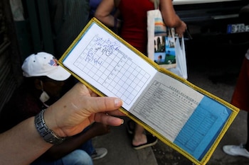 Una mujer muestra su libro de raciones, conocido localmente como la "libreta", para comprar productos en una tienda estatal subsidiada, o "bodega", en medio del brote de COVID-19, en La Habana, Cuba, el 22 de abril de 2020.REUTERS/Stringer