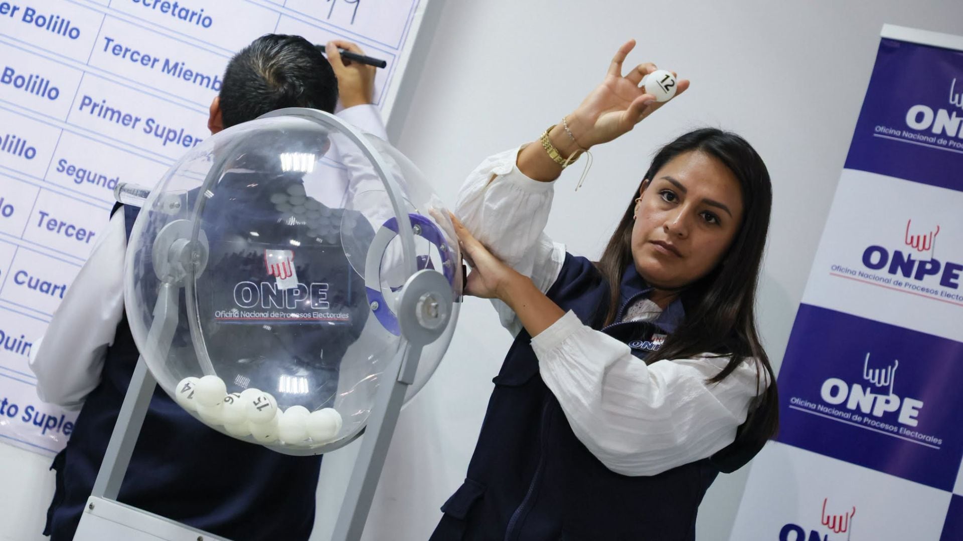 Una funcionaria de la ONPE muestra una bolilla con el número 12 durante el sorteo público de miembros de mesa para las elecciones municipales en Perú. (ONPE)