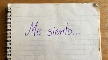 Primer plano de una hoja de cuaderno rayada con espiral a la izquierda, mostrando la frase "Me siento..." escrita en tinta morada.