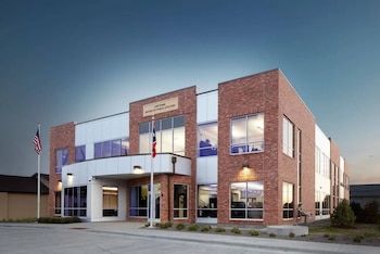 Edificio de ladrillo y paneles blancos con ventanas, cartel "Cheyenne Board of Public Utilities", bandera de Estados Unidos y otra bandera en mástil