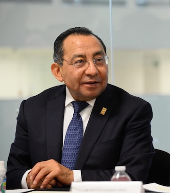 Juan Carlos Galván Cedillo, juez, sentado a una mesa, vestido con traje oscuro, camisa blanca y corbata azul, con gafas, mirando a la derecha