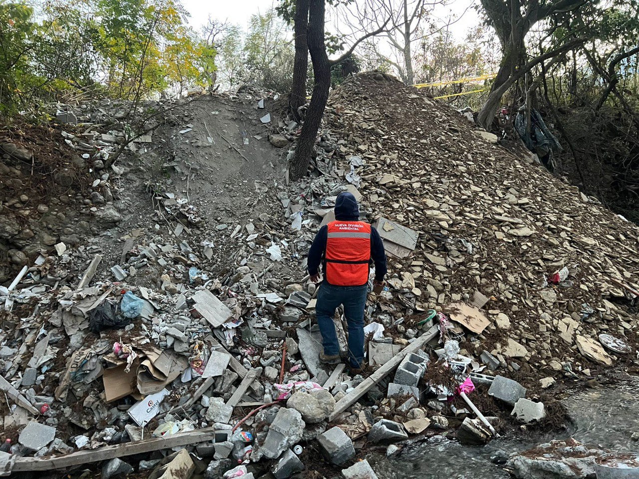 Un oficial inspecciona un área seriamente contaminada por desechos, evidenciando la necesidad de la reforma legal que busca imponer multas y prisión por el daño ambiental.